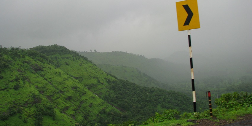 Tourists trekking uphill on a rocky trail surrounded by greenery at Matheran hill station–hill stations in kottayam