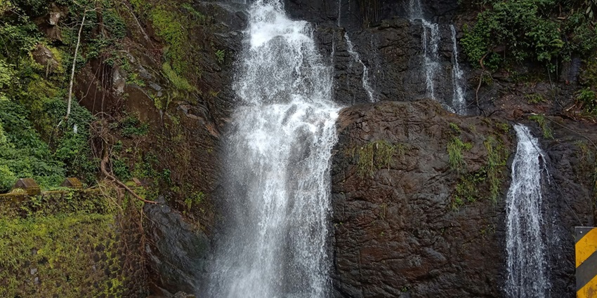 A mesmerising view of waterfall in Kerala with free flowing water over lush rocks.
