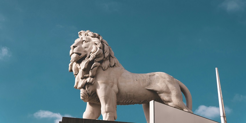 A mesmerising view of a white statue of a standing lion in a park during the daytime.