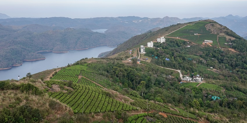 Enchanting view of the green hills of Kerala with a sparkling body of water on the side.