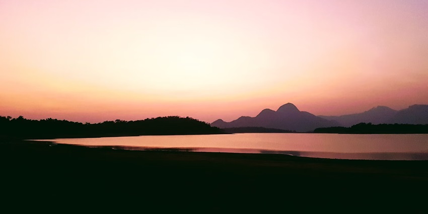 A fascinating view of the Malampuzha Dam during sunset with an orange sky in the backdrop.