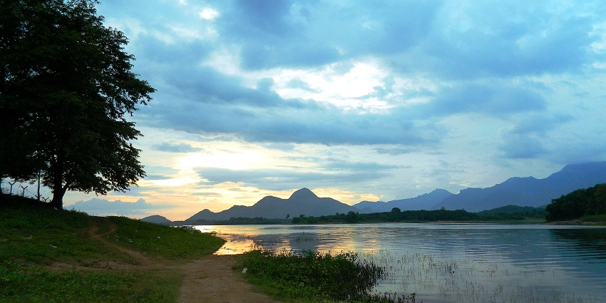 Sunset and bright sky hues dancing on the sparkling waters alongside a serene shore