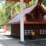 Stunning view of a red-roofed wooden structure in Malappuram surrounded by lush greenery.