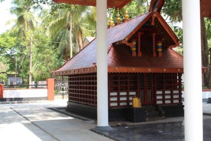 Stunning view of a red-roofed wooden structure in Malappuram surrounded by lush greenery.