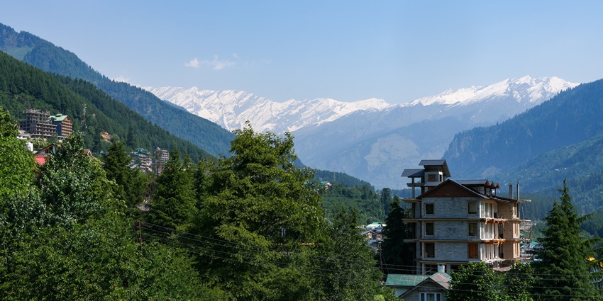 A picture of the scenic mountains in Manali taken on a bright sunny day with trees and greenery all around
