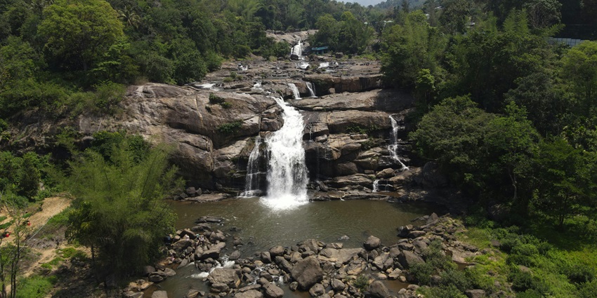 Small pathanamthitta waterfalls cascading over mossy rocks in a lush green forest setting