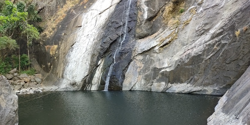 A stunning view of Marmala Waterfalls falling down a rock inside the thick green forest.