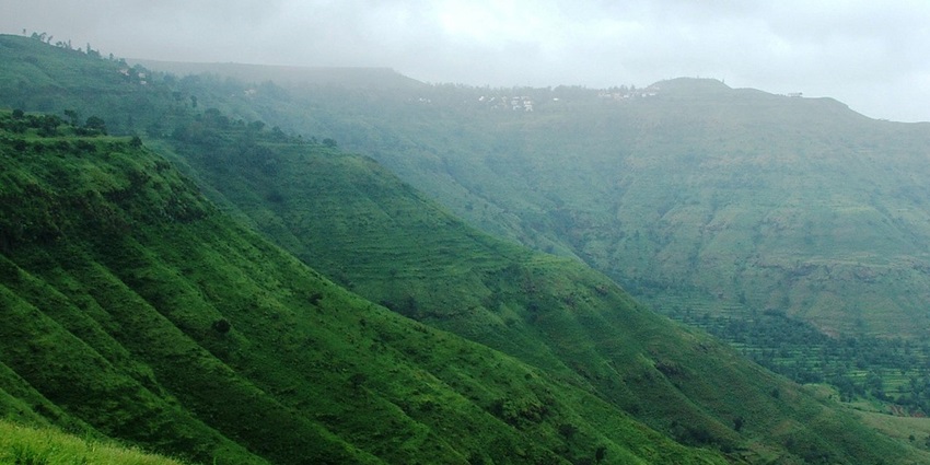 Scenic view of \ Hill with lush greenery, rolling slopes, and a clear blue sky.