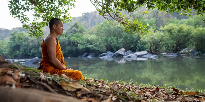 A Buddhist monk meditating on the riverside