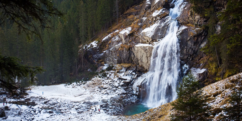 A scenic waterfall slowly cascading down a rocky terrain, surrounded by lush greenery