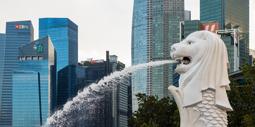 A view of the Merlion fountain at a Singapore park with views of tall skyscrapers in the background