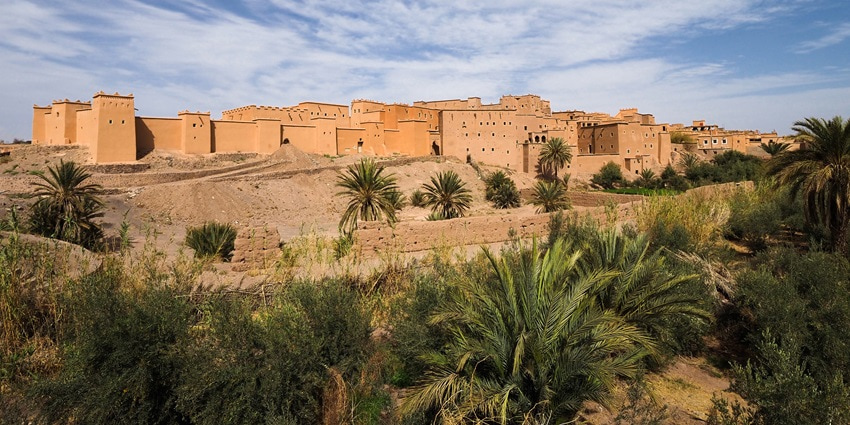 A scenic view of a historic castle built in the 17th century, surrounded by desert and palm trees