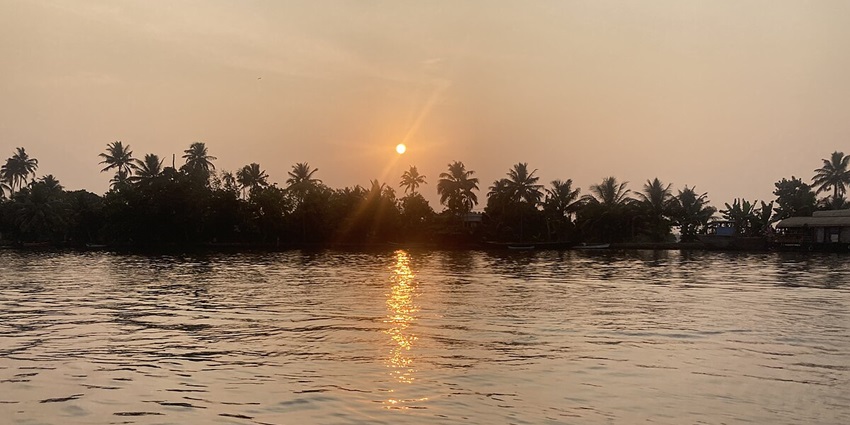 A mesmerising sunset view above a water body in Kerala with lush greenery all around