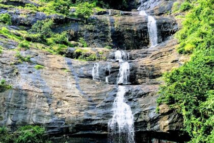 A breathtaking view of a waterfall in Munnar flowing through rocks surrounded by greenery.