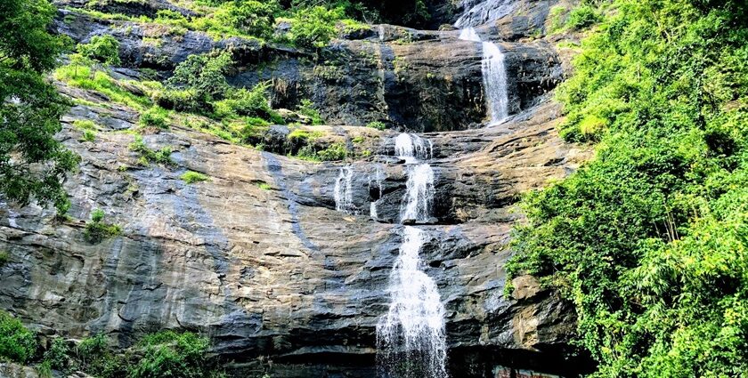 A breathtaking view of a waterfall in Munnar flowing through rocks surrounded by greenery.