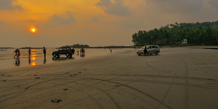 Vibrant sunset hues reflecting in the waters of Muzhappilangad drive-in beach