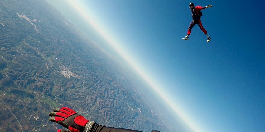 A man in red and black outfit, diving in the air seeking the thrill of a lifetime.