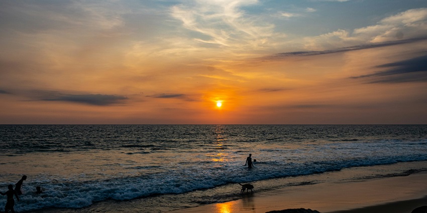 A breathtaking view of a beach in Kerala over a golden sunset with light and soft waves.