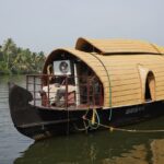 Houseboat on waters of Nedumudy, surrounded by lush greenery - water sports in Kerala