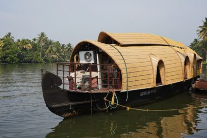 Houseboat on waters of Nedumudy, surrounded by lush greenery - water sports in Kerala