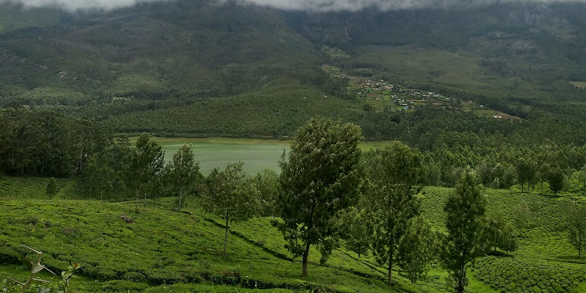 Landscape view containing lake, clouds, hills, tea estate during monsoon season in Kerala