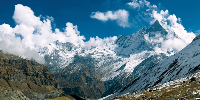 A breathtaking view of snow-capped mountains with a scenic backdrop of cloudy skies