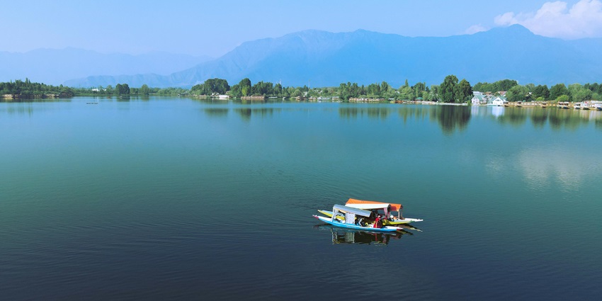 View of boats on the Nigeen lake with its azure blue waters and green forests