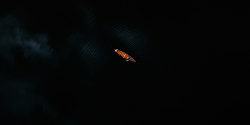 An eagle-eye view of a person indulging in the adventure of kayaking at night.