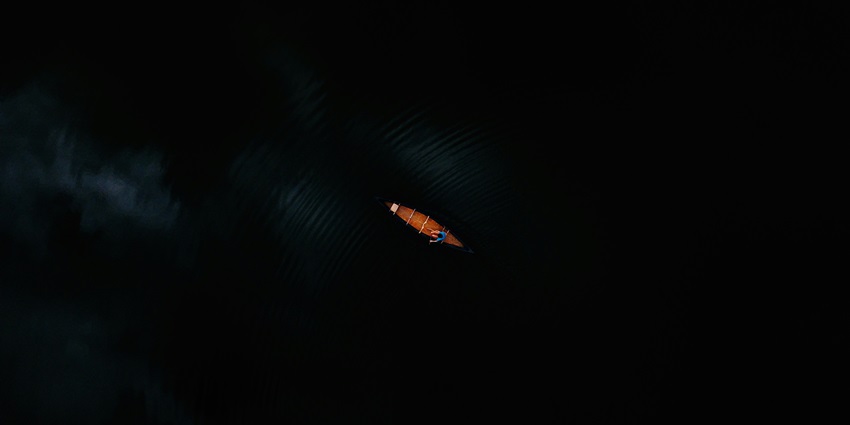 An eagle eye view showing a person indulging in the kayaking adventure at night.