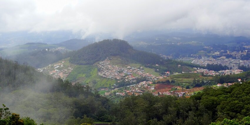 An aerial view of the hills in Ooty that have a misty appearance and cool climate