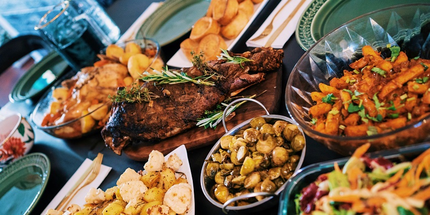 A festive table filled with roast meat, potatoes, vegetables, and vibrant fresh salad.