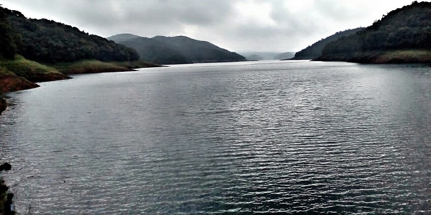 Clouds reflecting on the serene waters of the lake, encircled by luscious hills