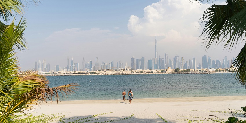 A stunning view of a beach in Dubai with the skyline in the background during the day.