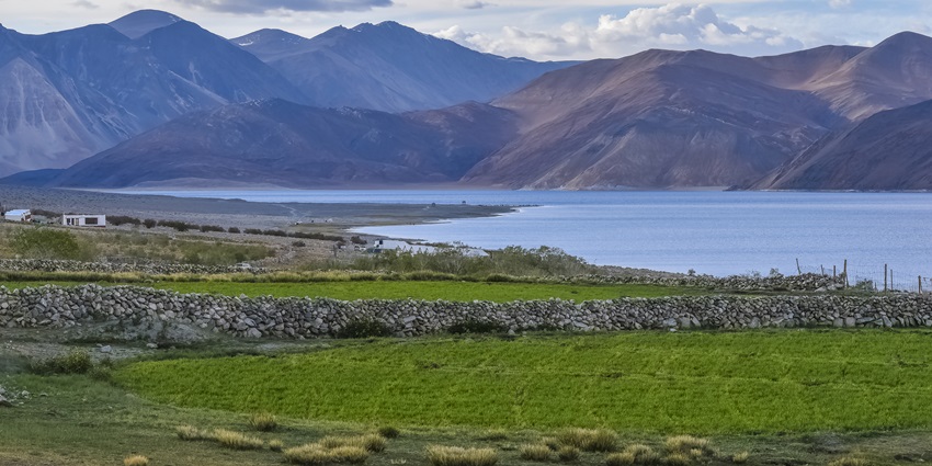 The serene blue waters of the Pangong Tso Lake in Leh with clouds in the backdrop