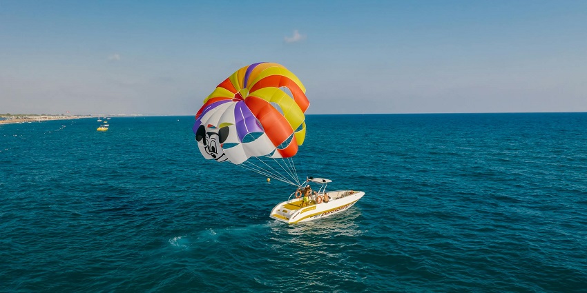 A view of a parachute being deployed by tourists while parasailing above a motorboat.
