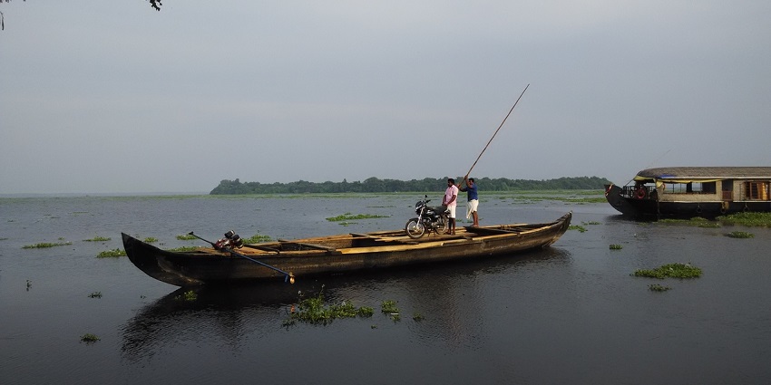 View of Pathiramanal Island, two men boating around lush greenery view and clear water.