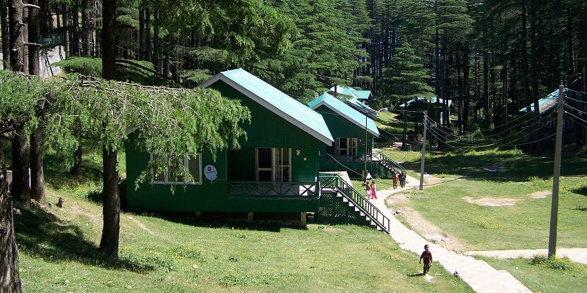 An image with the view of Patnitop cottages surrounded by lush greenery and mountains.