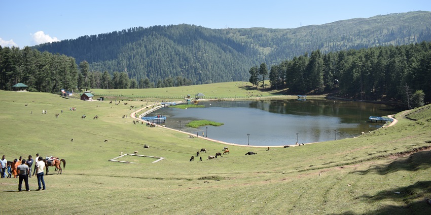 A picture of a hill station in Kashmir with a blanket of greenery all around and a mesmerising lake