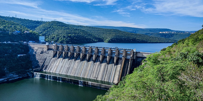 A serene view of the Pattisseri Dam featuring shimmering blue waters and lush greenery.