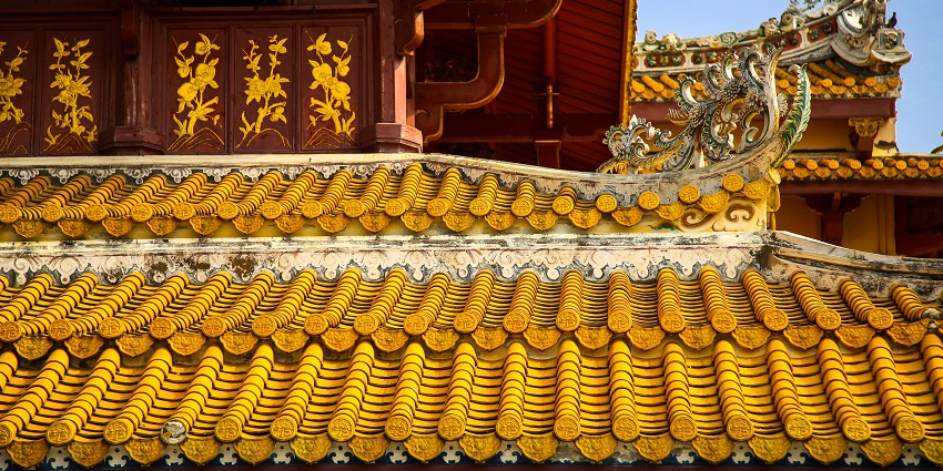 A close-up view of a golden and red temple with unique architecture during the daytime.