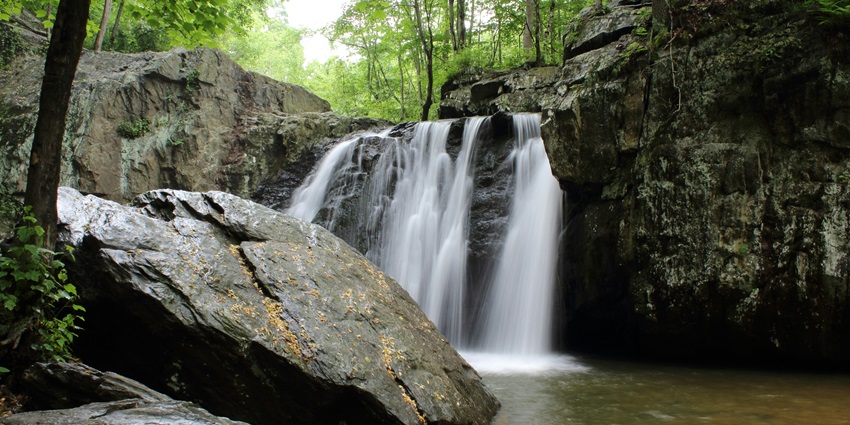 A picture of a serene waterfall with water cascading down a rocky terrain