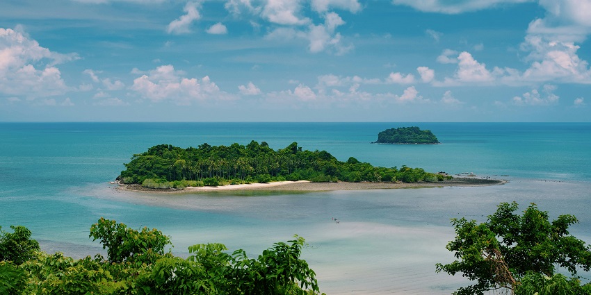 Wide-angle view of the island from far away, surrounded by crystal clear waters