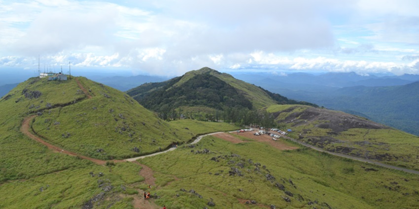 Verdant landscapes of the Ponmudi hills overlooking the vast sky and foggy mountains beyond