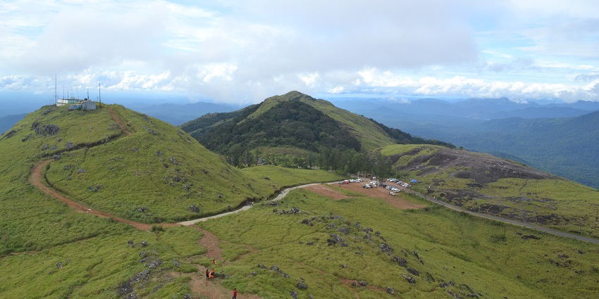 Misty hills with lush greenery and winding mountain roads - hill stations near Trivandrum