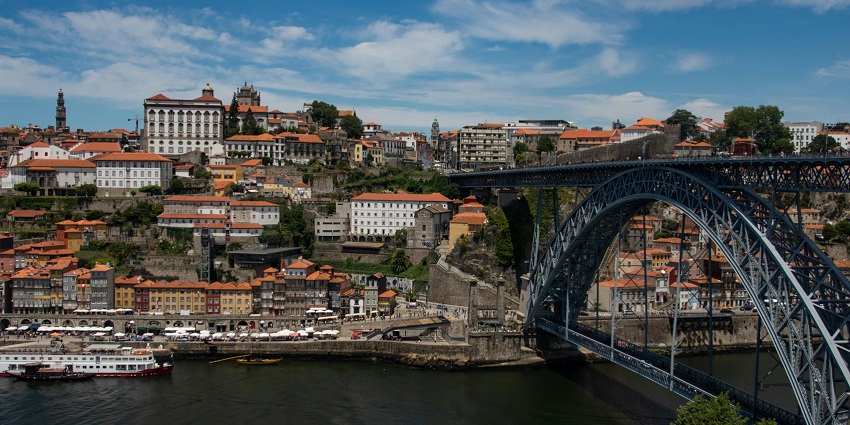 A mesmerising view of Portugal city with a stunning black bridge over the river flowing by