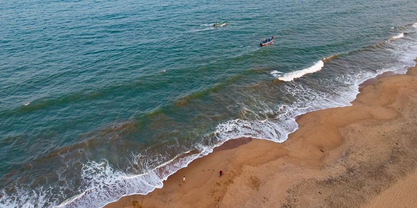 An aerial view of turquoise water and golden sands of a beach in Puducherry, India
