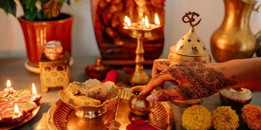 Hand of a Person with Mehandi Touching a Gold Cup Traditional Ritual Decorations on Table