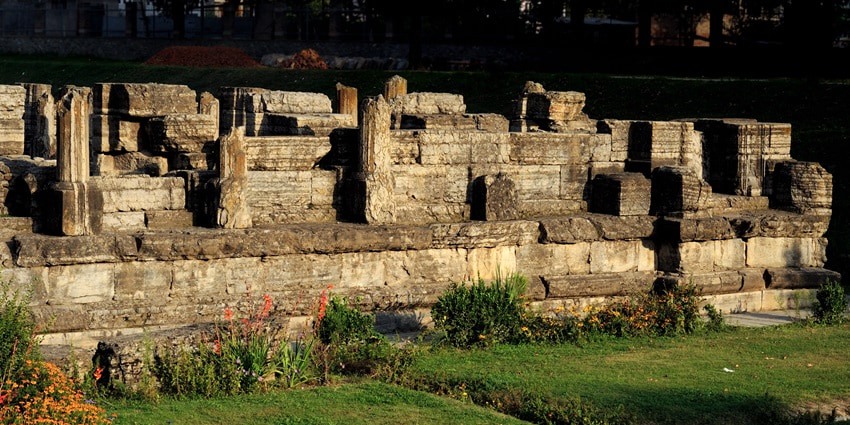 A picture of a historical temple in Pulwama with a garden area in front of it