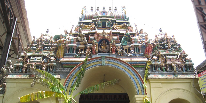 A close-up view of the Punnainallur Mariamman Temple in Kerala with green plants in front.