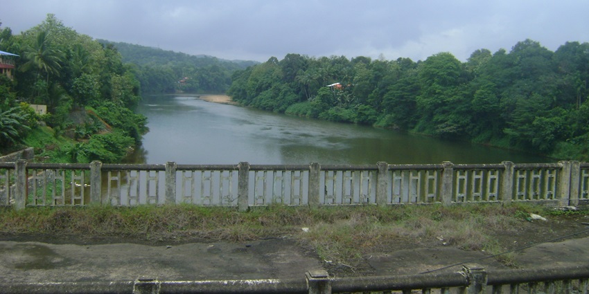 Remains of the old collapsed Ranni bridge surrounded by greenery and a serene river.